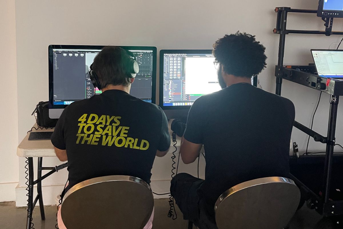 View from behind of two crew members working on desktops with one wearing headphones