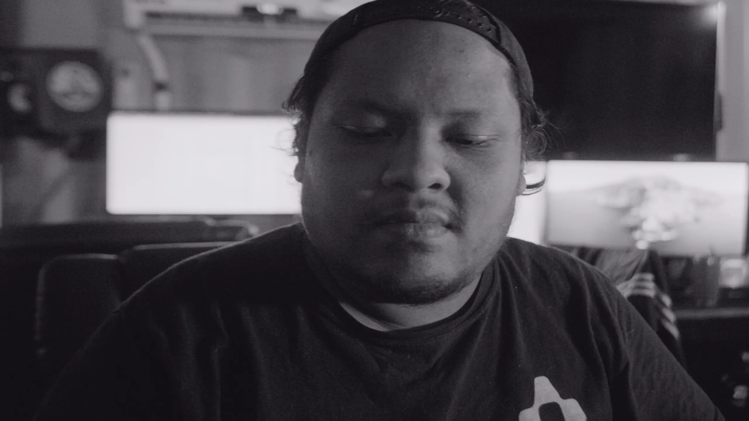 Chris Acosta 1 Black and white of Chris Acosta wearing cap on backwards looking down