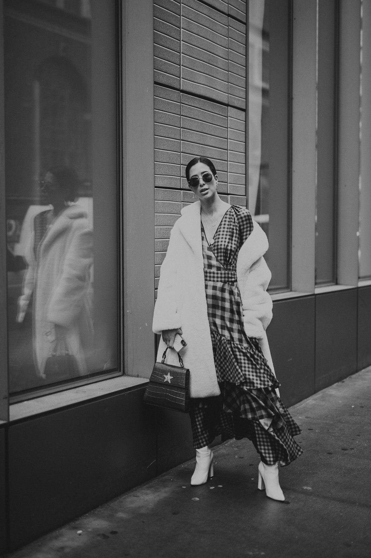 Los Angeles Video Marketing Services Black and white of woman wearing a dress, thick coat and high heeled shoes standing on a sidewalk in a city