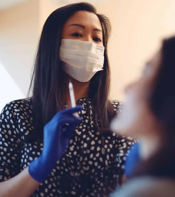 cis-portfolio-the-practice3 Female dental assistant wearing a white mask looking at patient