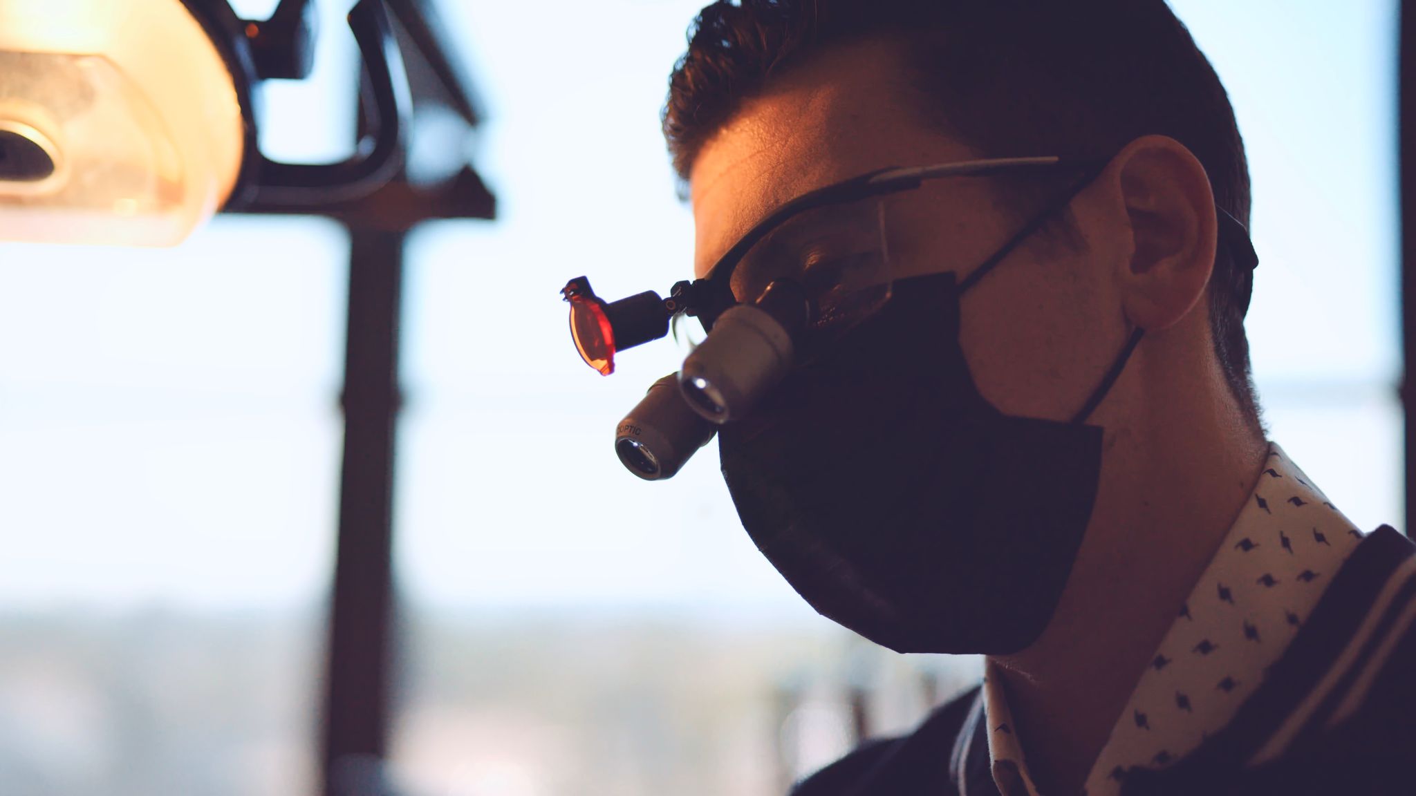 Side profile headshot of dentist wearing a black mask