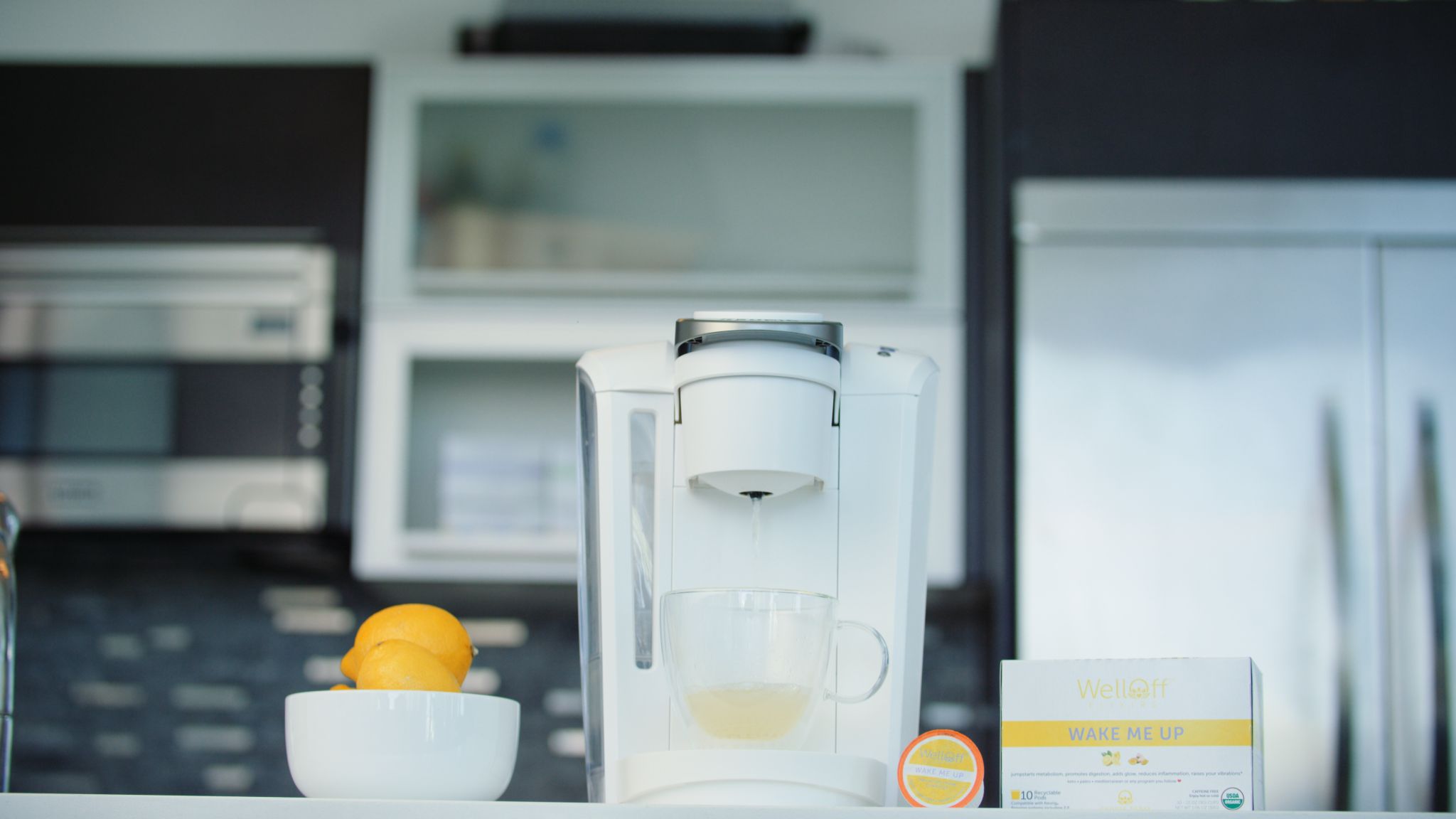 Wake Me Up product on display with bowl of lemons and drink maker in a kitchen