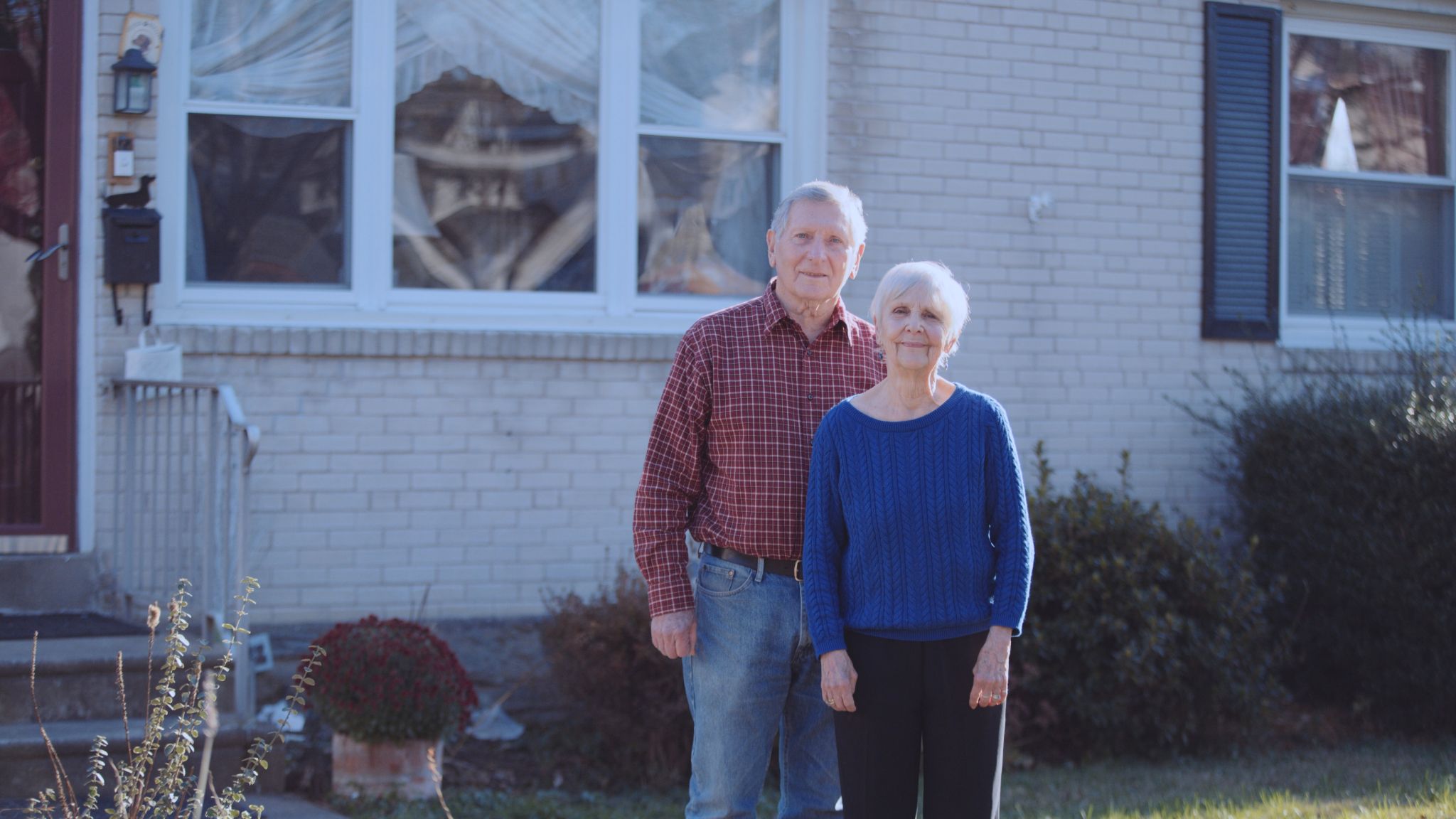IU C&I Studios Portfolio 76 words Maria Mclaughlin Still Older man and woman standing in front of house