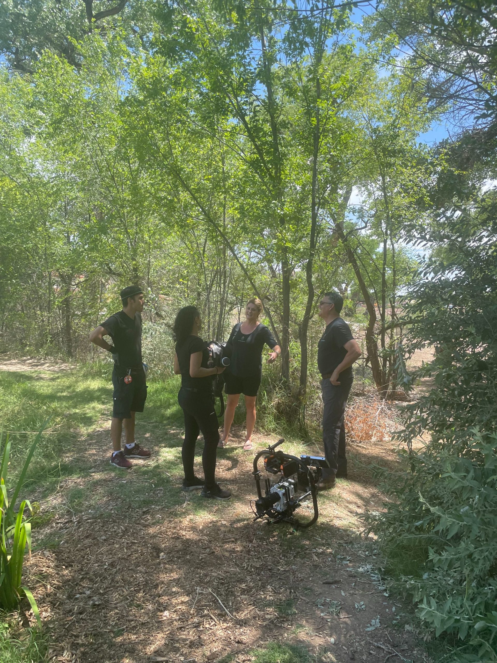 IU C&I Studios Portfolio Two men and two women talking in a forest with video equipment on the ground nearby