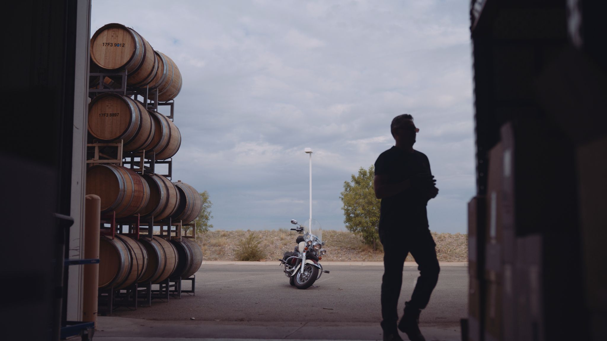 IU C&I Studios Portfolio Taylor Garrett Spirits with silhouette of him in a warehouse with motorcycle and alcohol barrels in the background