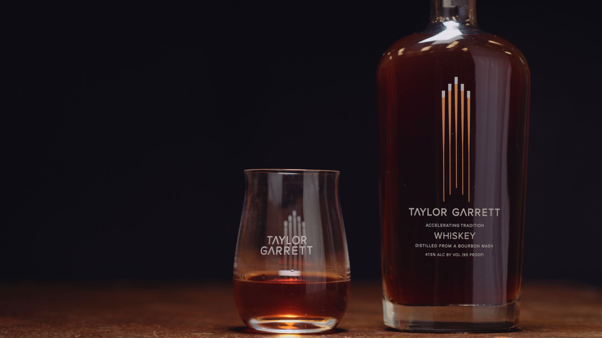 IU C&I Studios Portfolio Taylor Garrett Spirits Glass containing some whiskey as well as bottle on display on a wooden table