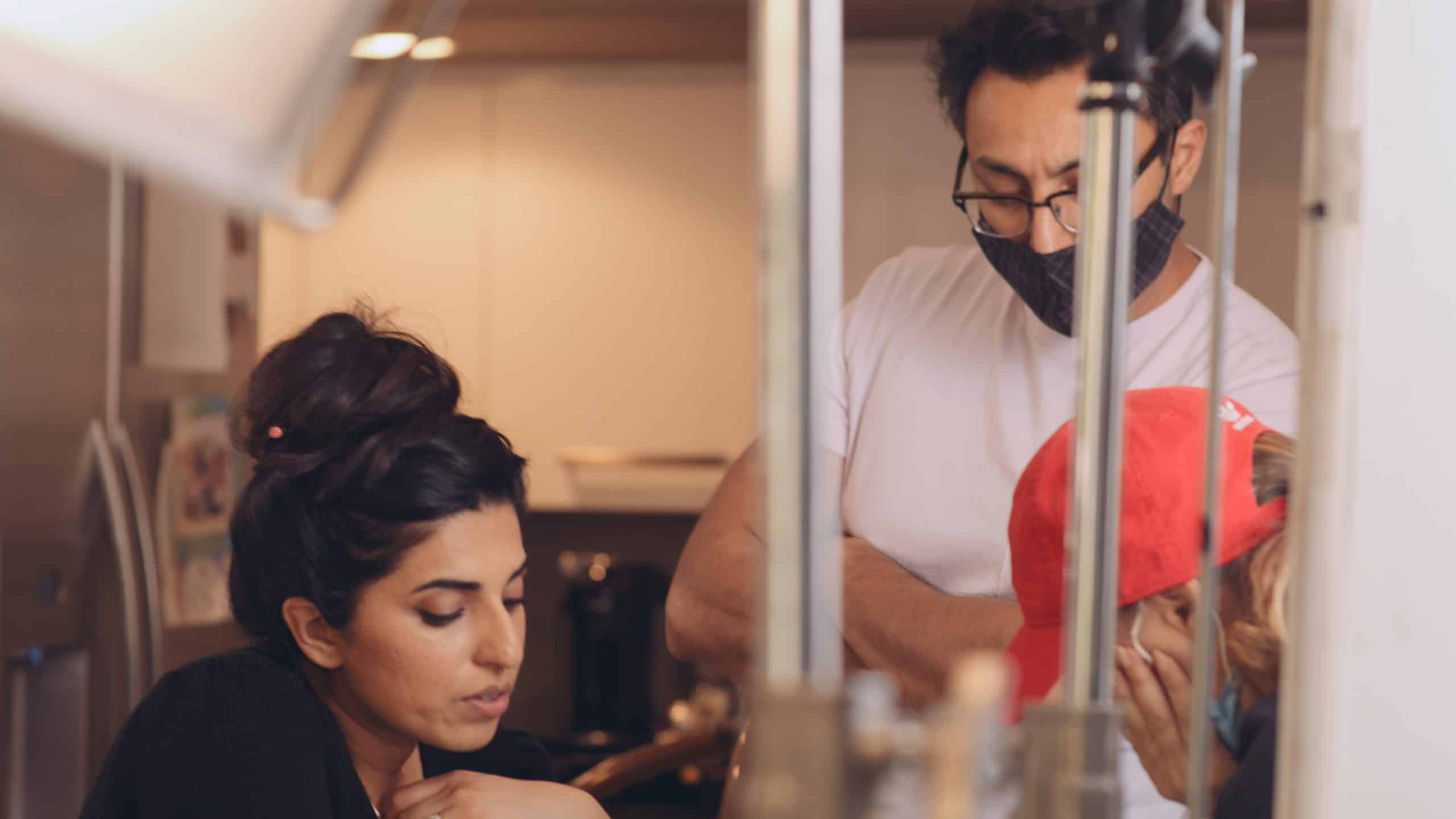 Woman with long hair in a bun with two crew members going through notes