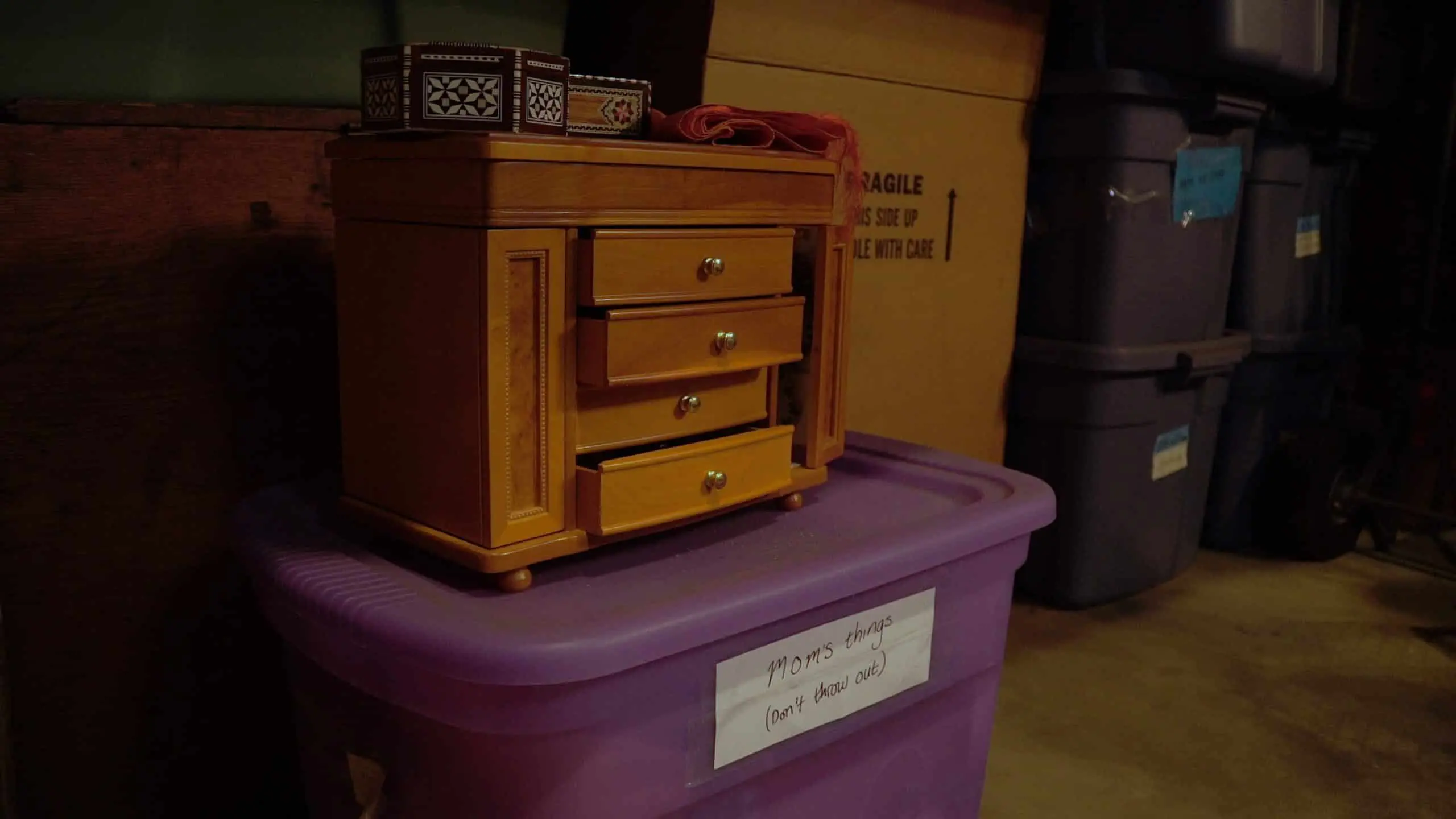 Bart McCarthy - Q Guy 14 Closeup of small table with drawers sitting on a purple tote in a storage room with other totes and boxes