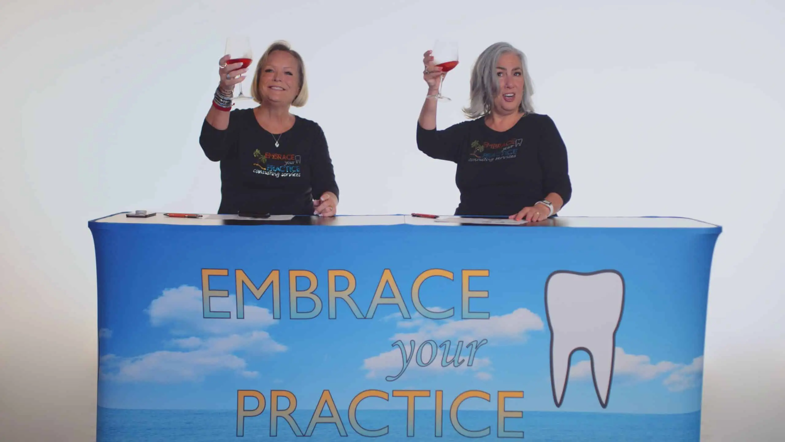 Embrace Your Practice 10 Two women sitting at a table with banner toasting glasses with red wine smiling for the camera