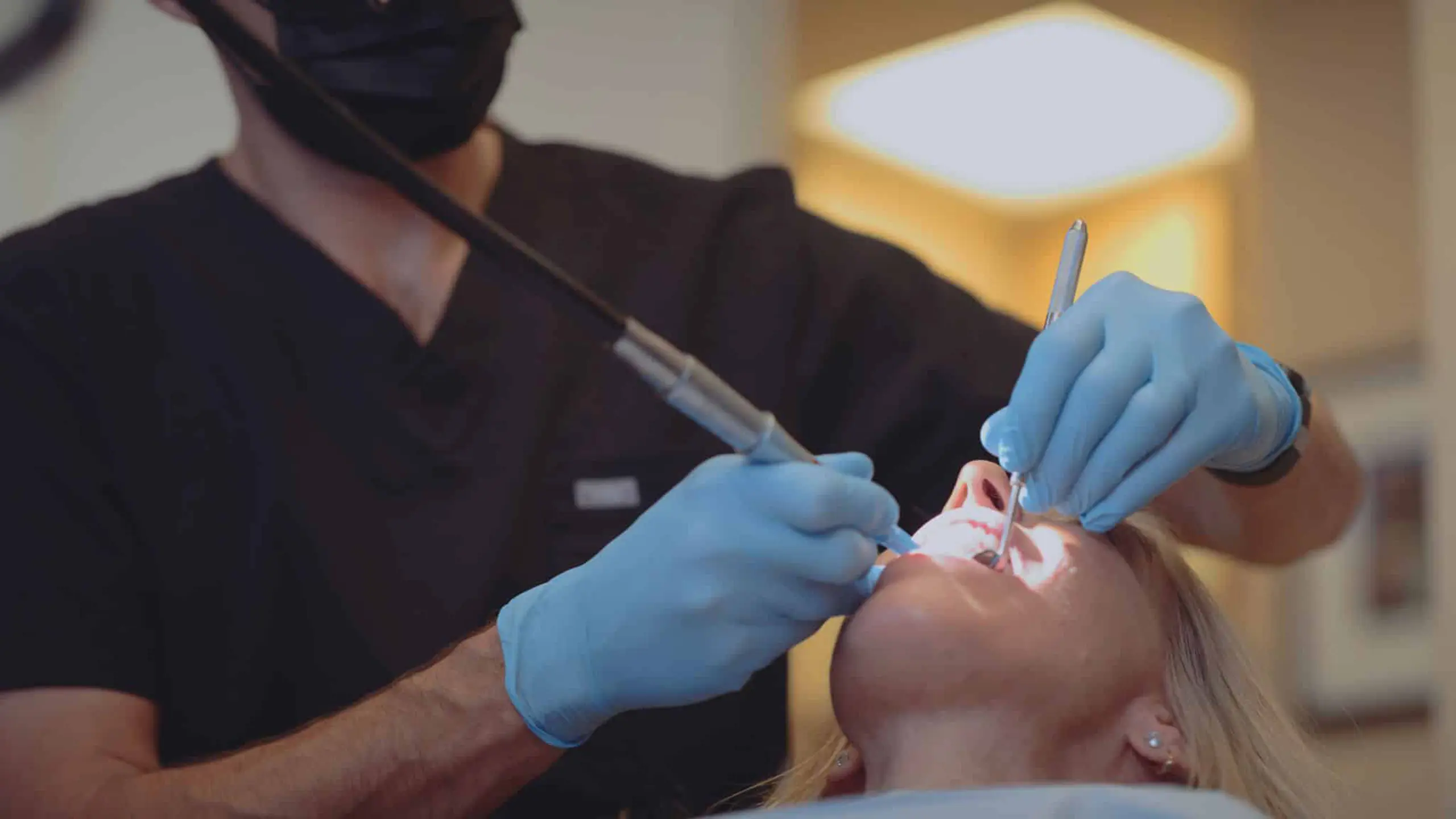 Pierce Aesthetics 10 Male dentist wearing black mask working on a female patient