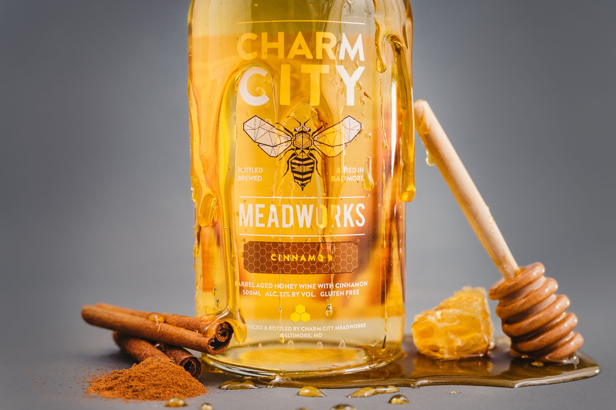 IU C&I Studios Page Charm City Meadworks Bottle of honey wine with cinnamon surrounded by honey and cinnamon ingredients