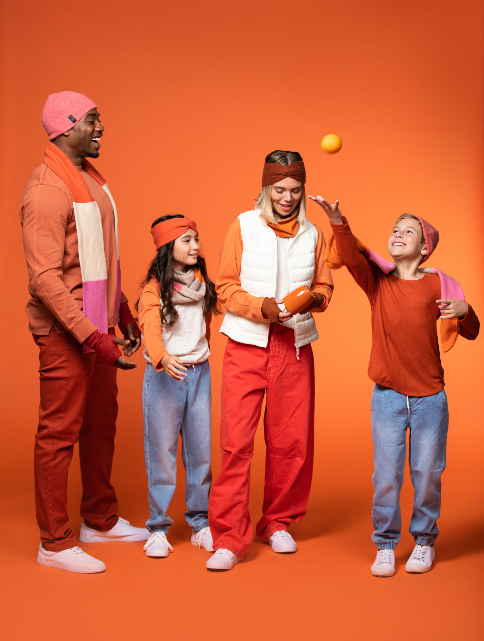 IU C&I Studios Page Top Left corner African American man, woman, girl and boy who is throwing up an orange against an orange background