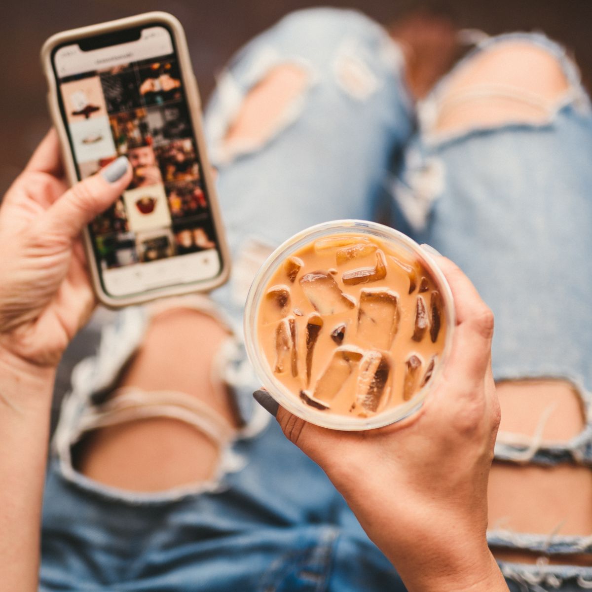 Steps to Creating a Business Video that Stands Out Closeup of person using a cell phone and holding iced coffee wearing torn jeans