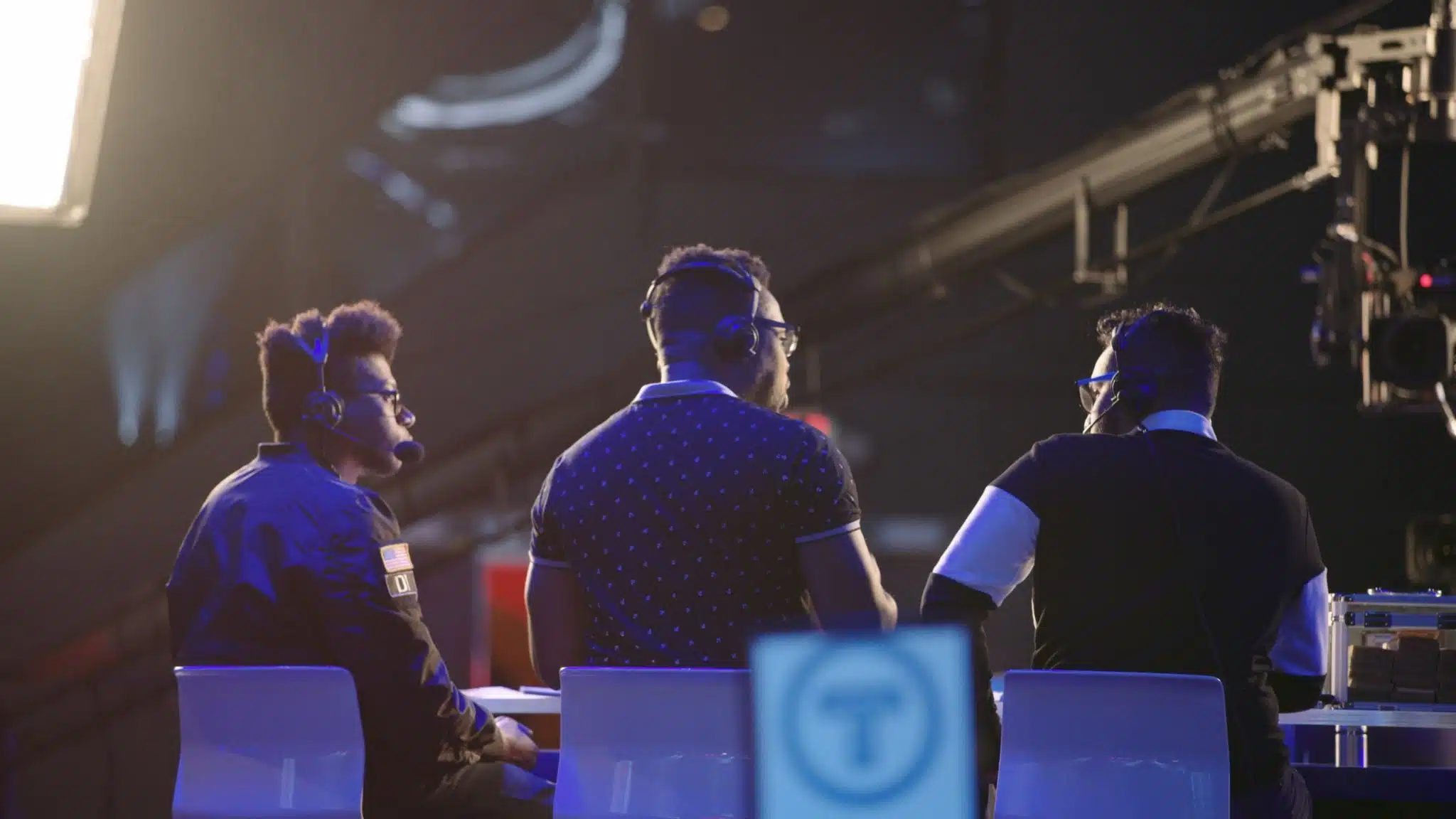 View from behind of three men on stage talking