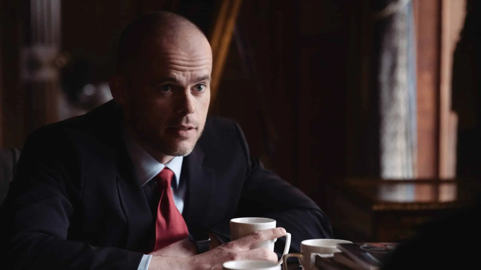 Bald man posing for camera holding a cup of coffee