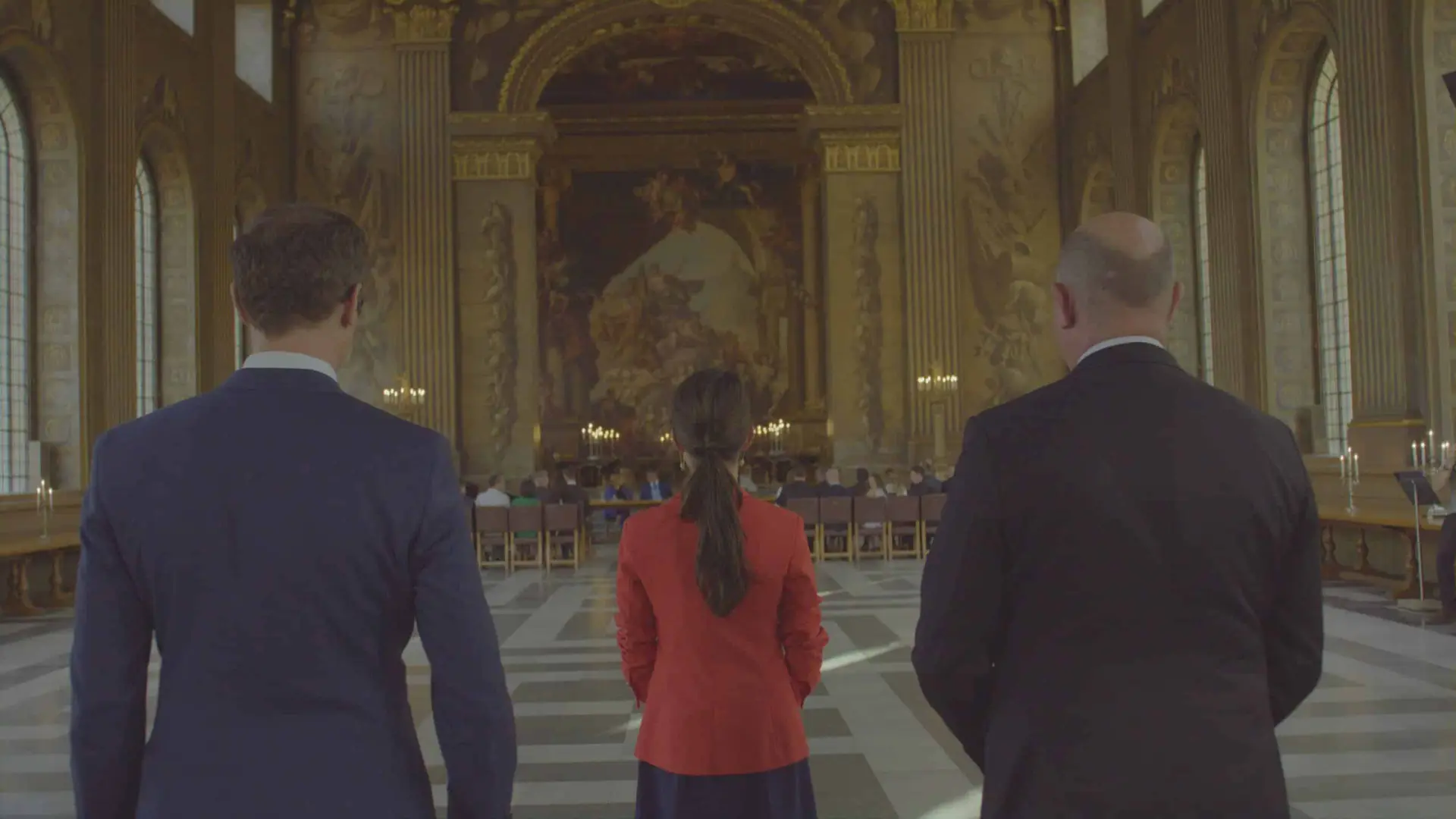 Two men and woman looking down long hall