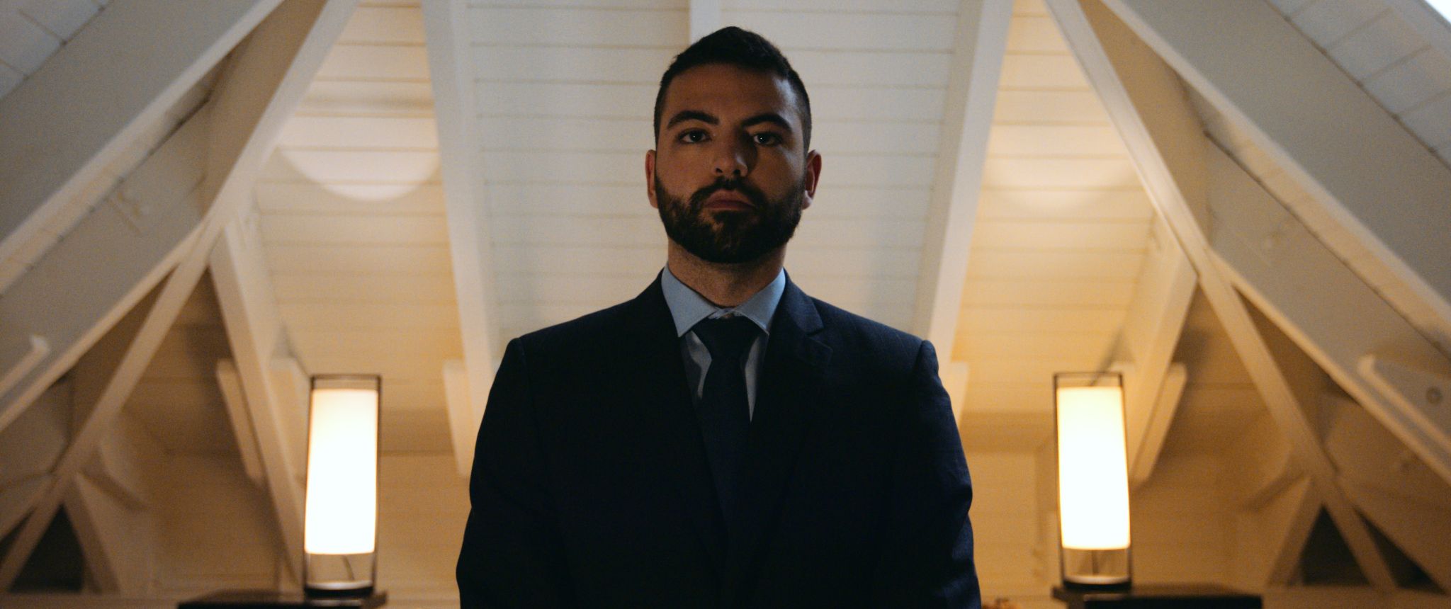 Man with short beard and hair looking down at camera