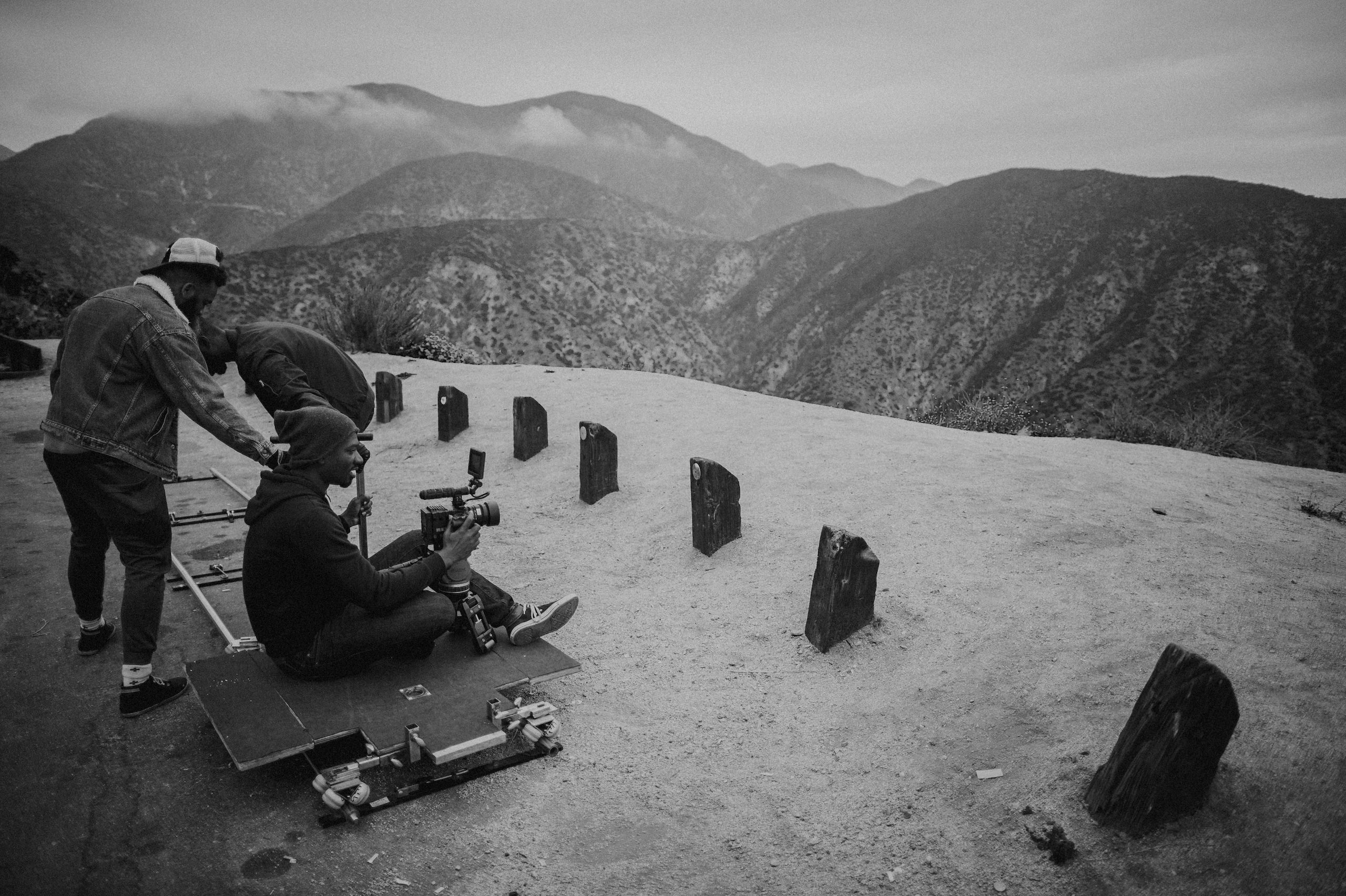 Black and white of a film crew setting up equipment on a cliff