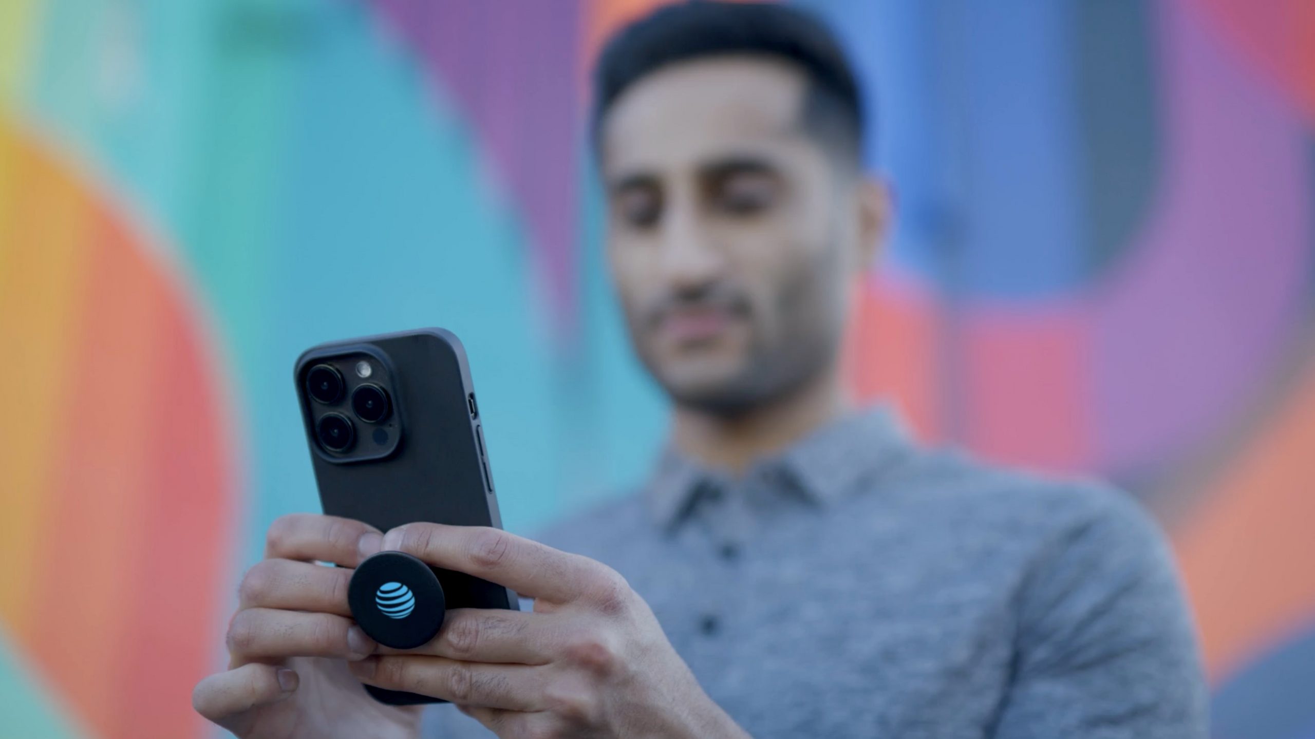 Man holding AT&T 5G enabled iPhone with AT&T logo on a pop socket