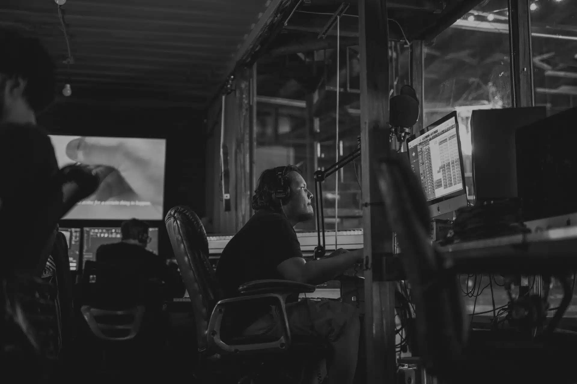 Black and white image of male wearing headphones using audio equipment.