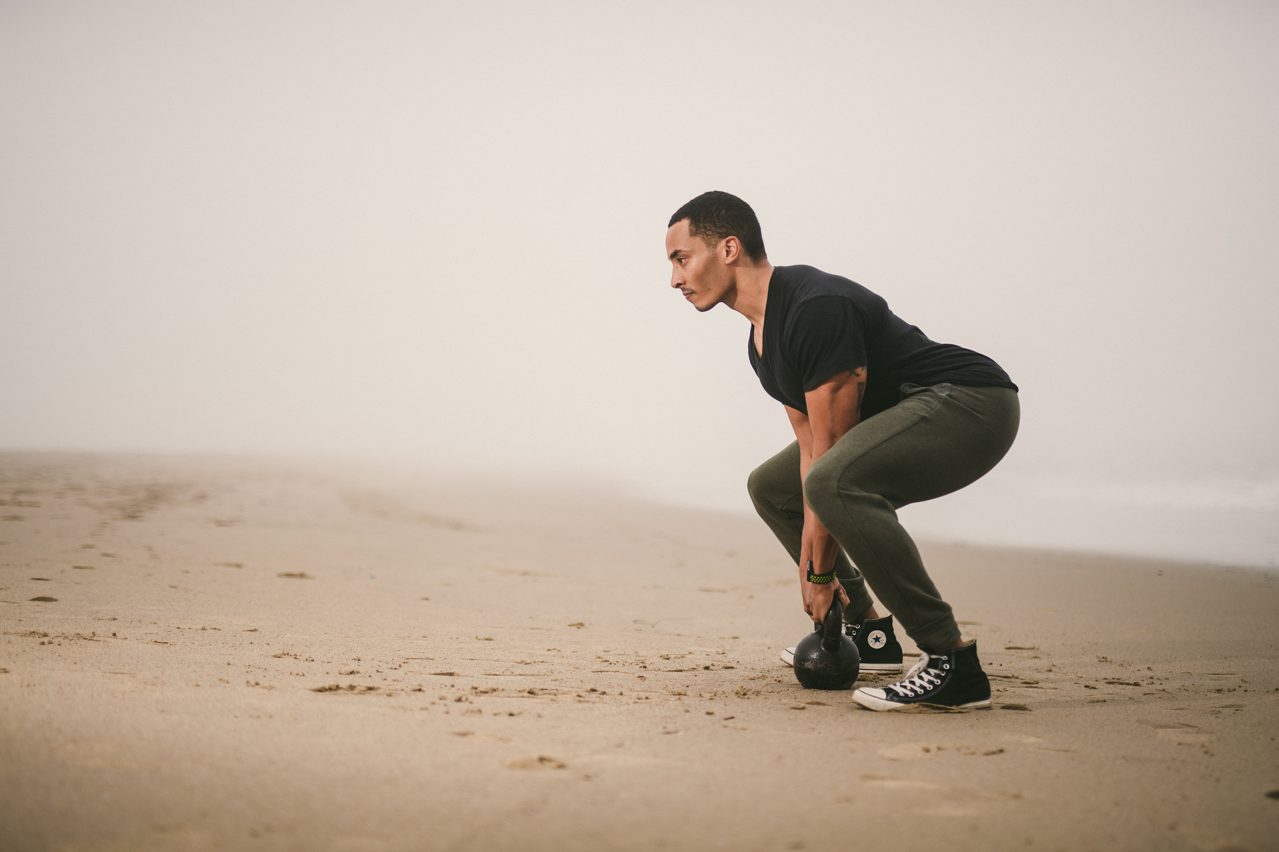 Health and Fitness Marketing Kinetix 365 Beach Exercises Man exercising with a kettle ball in the sand