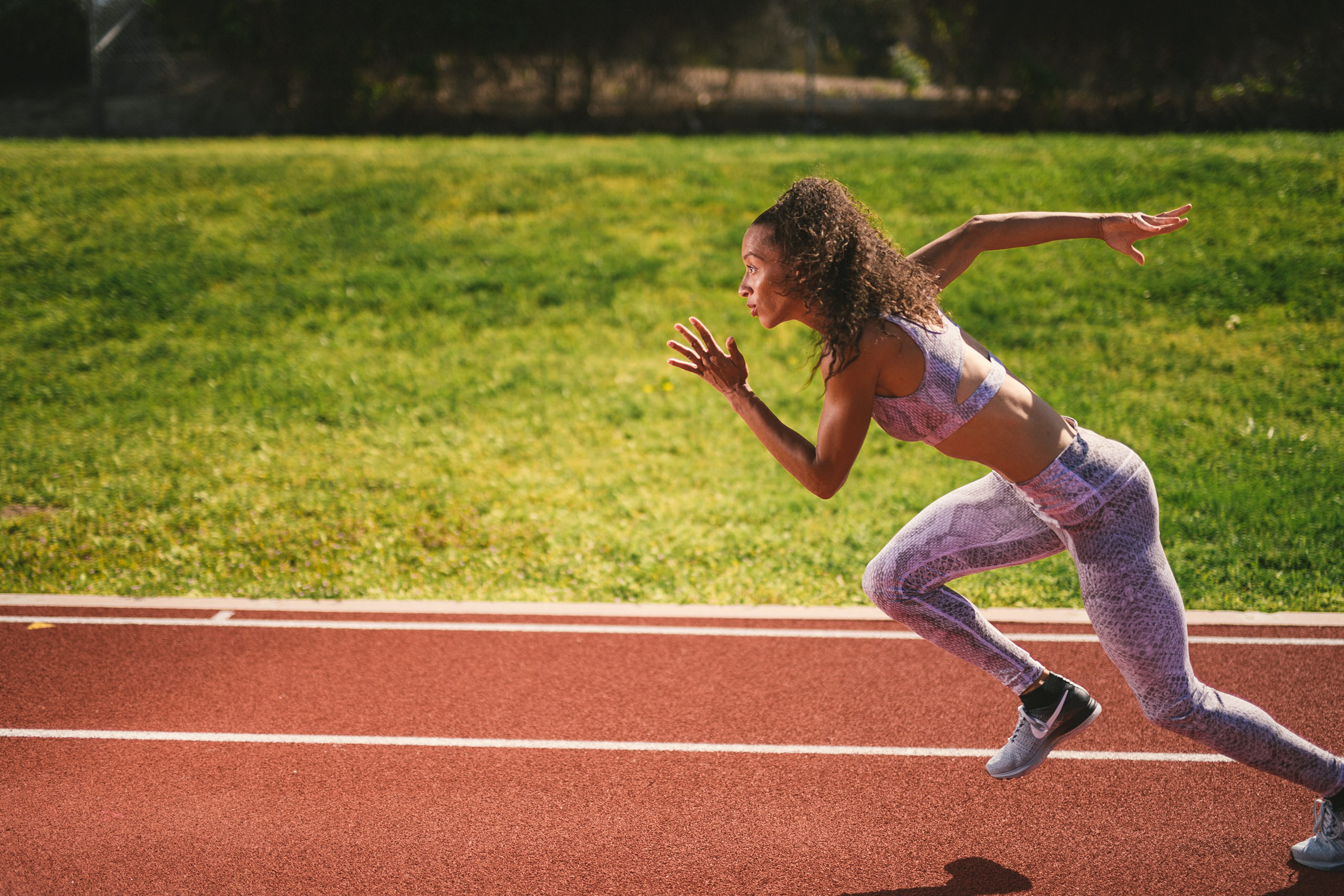 Professional Photography Services to elevate your brand C&I Studios Creative Marketing Kinetix 365 Side view of woman posing for camera in running pose on a track field in track outfit