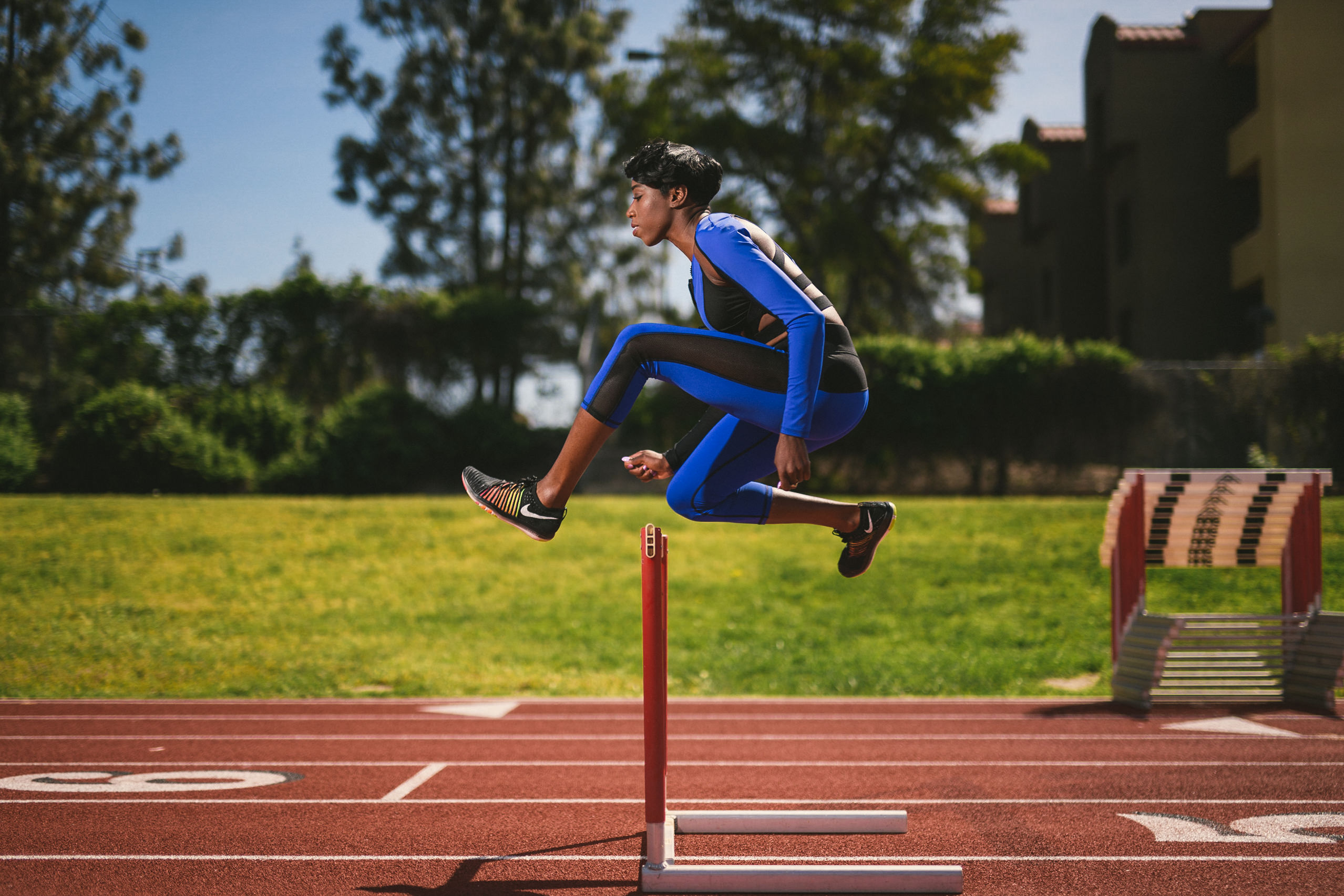 Professional Photography Services to elevate your brand C&I Studios Creative Marketing Kinetix 365 Side view of a woman on a track field in track outfit jumping a hurdle