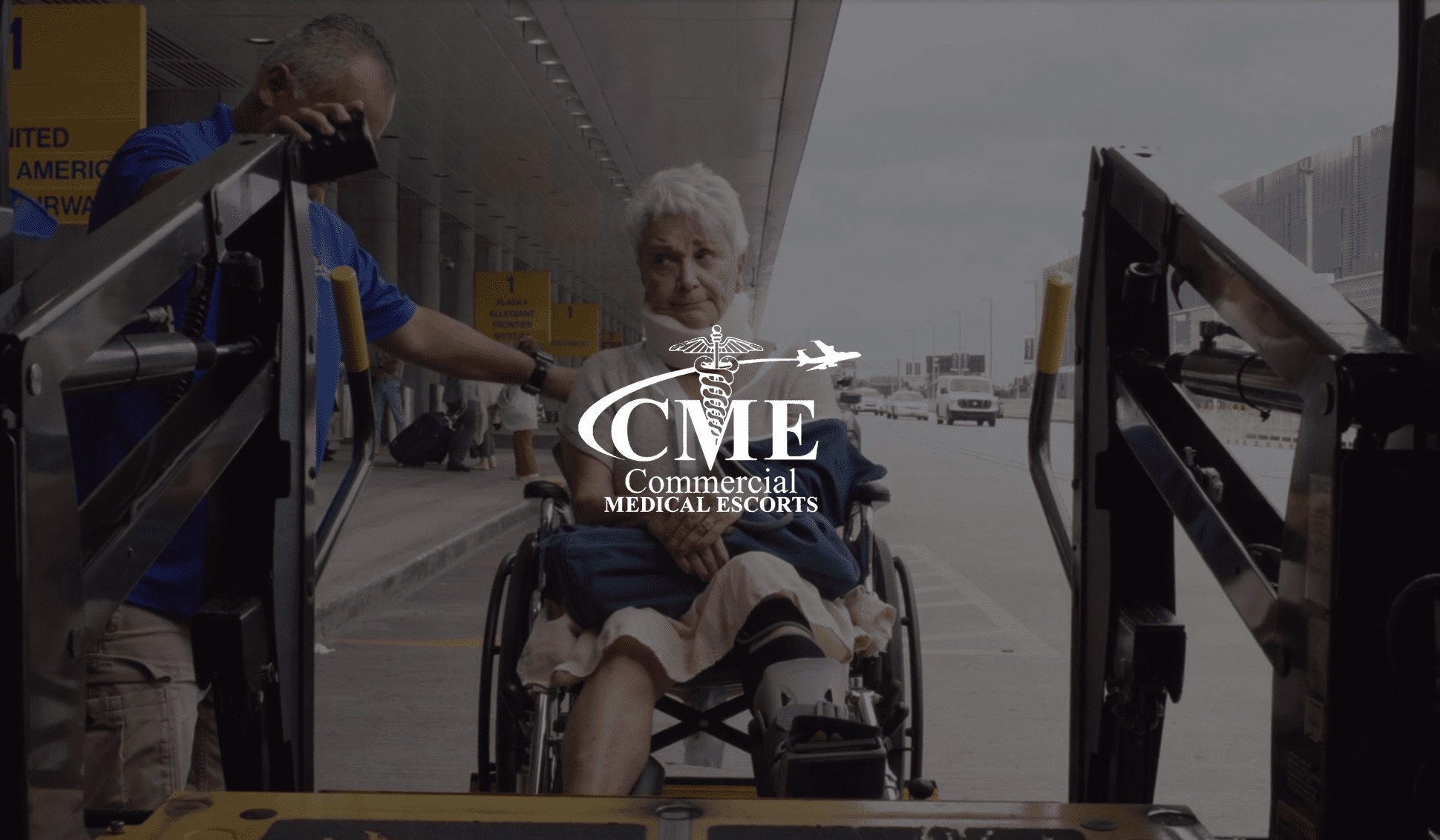White Commercial Medical Escorts logo with woman wearing a neck brace in a wheelchair being lifted into a transport vehicle with help of an assistant