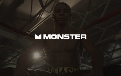 White Monster Music Cable Logo With Dimmed Background Of African American Boxer Standing In The Corner Of A Ring