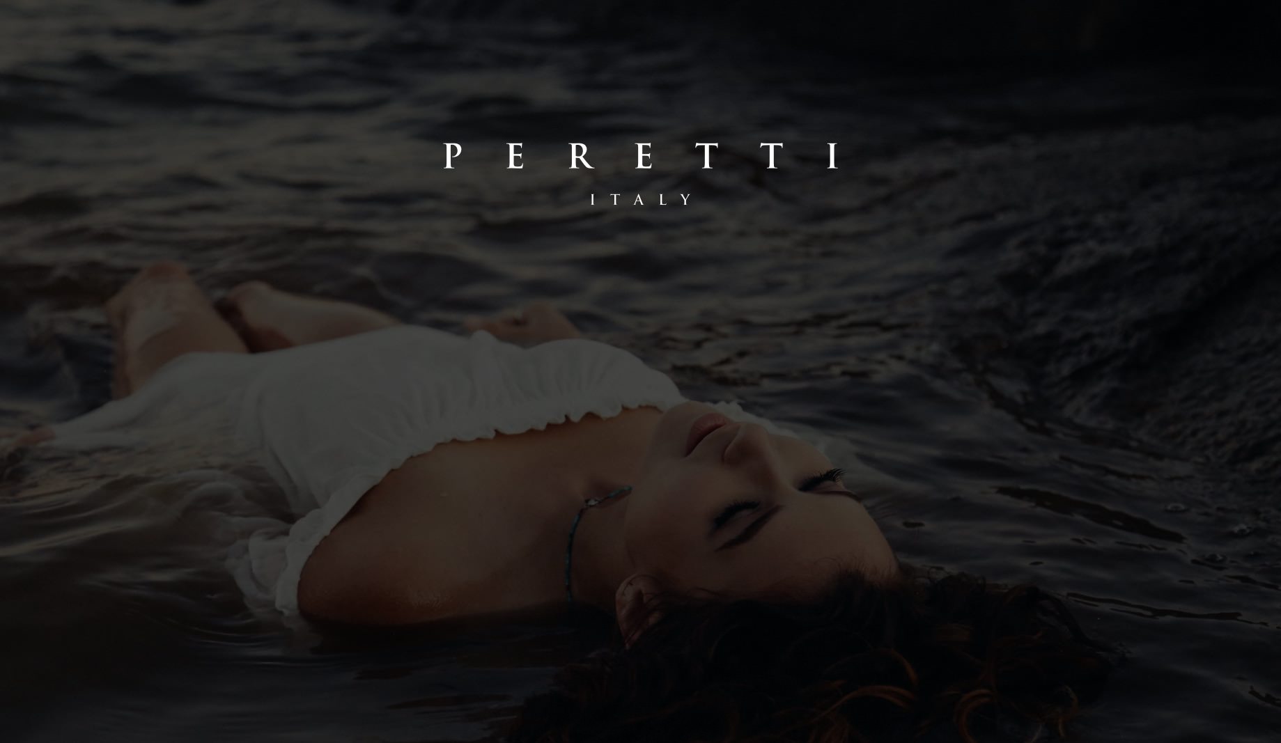 White Peretti Italy title on dimmed background of woman in a white dress laying in the water