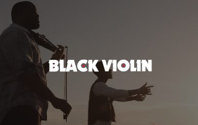 Red And White Black Violin Logo On Background Closeup Side Profile Of Man Playing Violin With Another Man Singing Next To Him