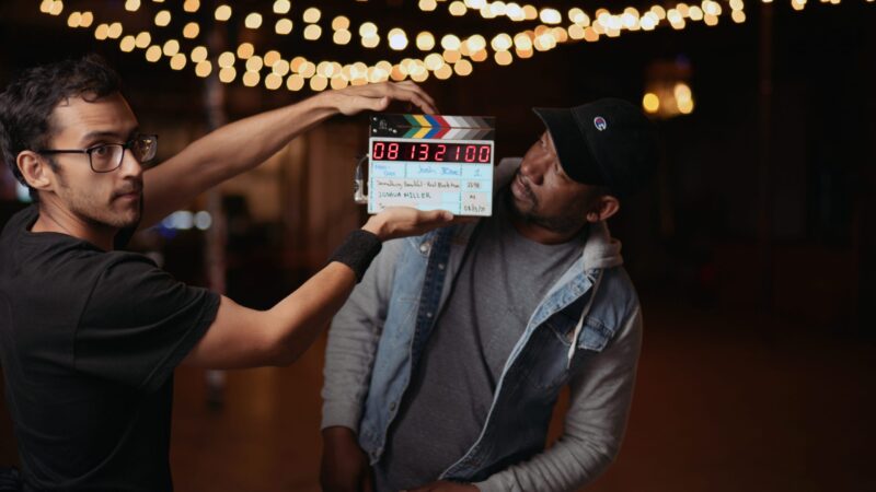 Steven Perez Using A Clapboard In Front Of Joshua Who Is Looking On