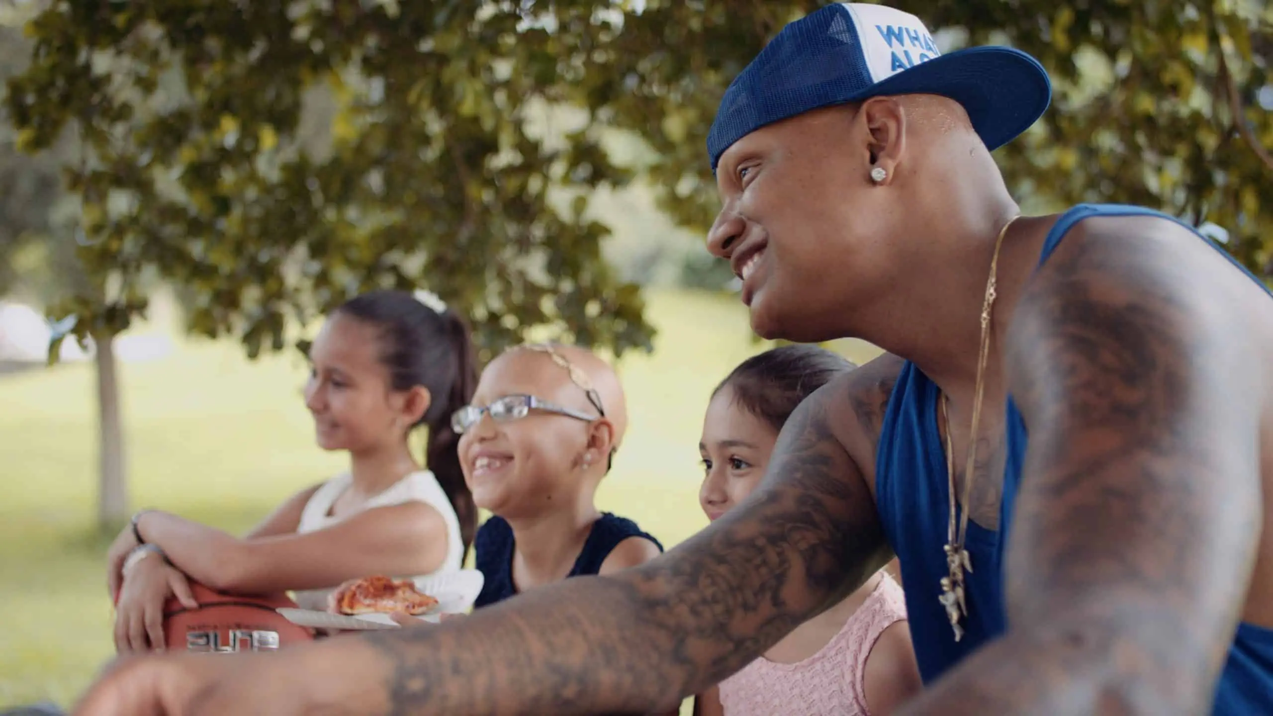 cis-page-what-is-alopecia10 Side profile of Charlie V wearing blue shirt smiling sitting next to three girls