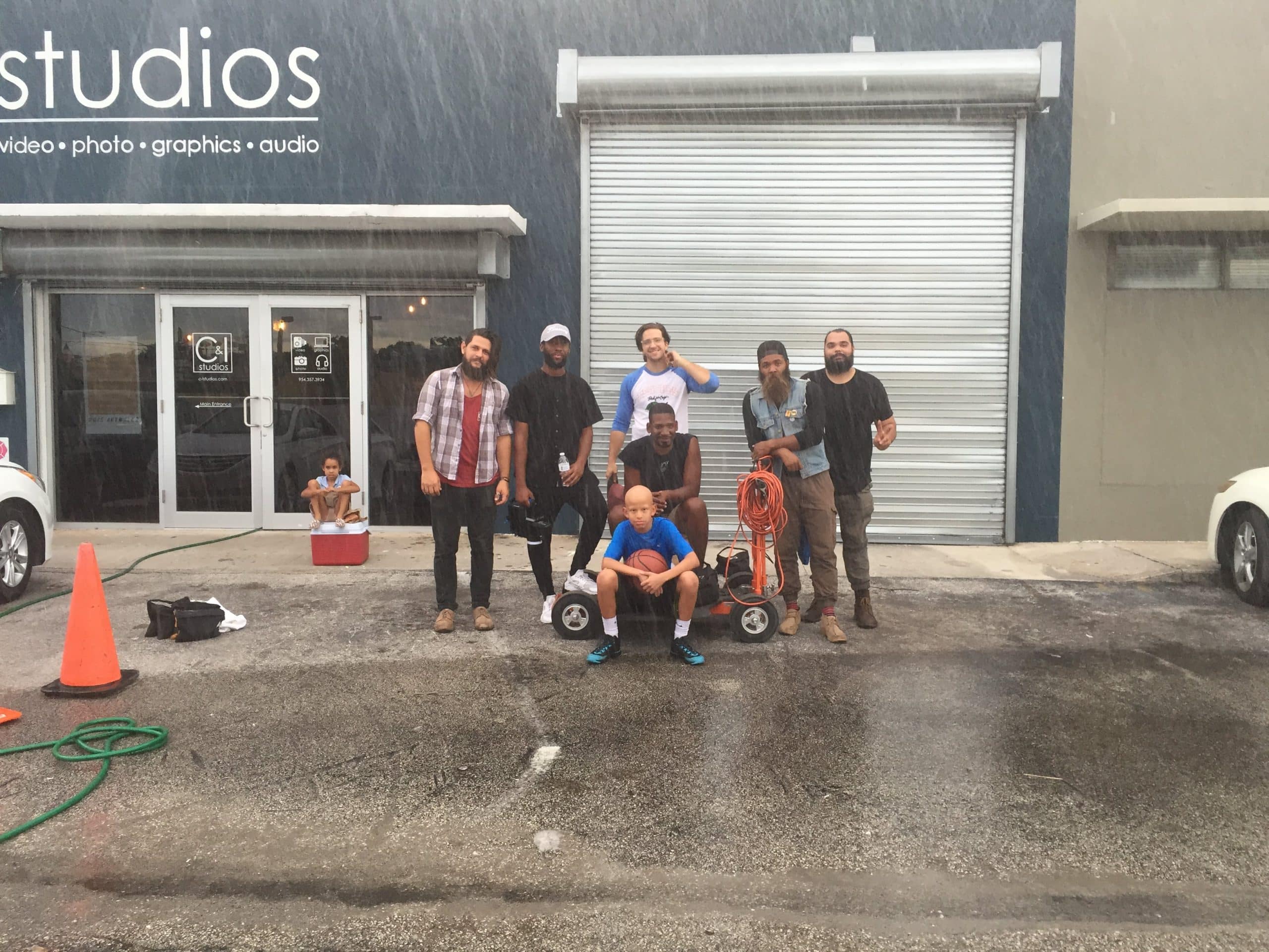 Charlie V What is Alopecia? Crew and Charlie V holding basketball posing for the camera in a group photo in front of the studios