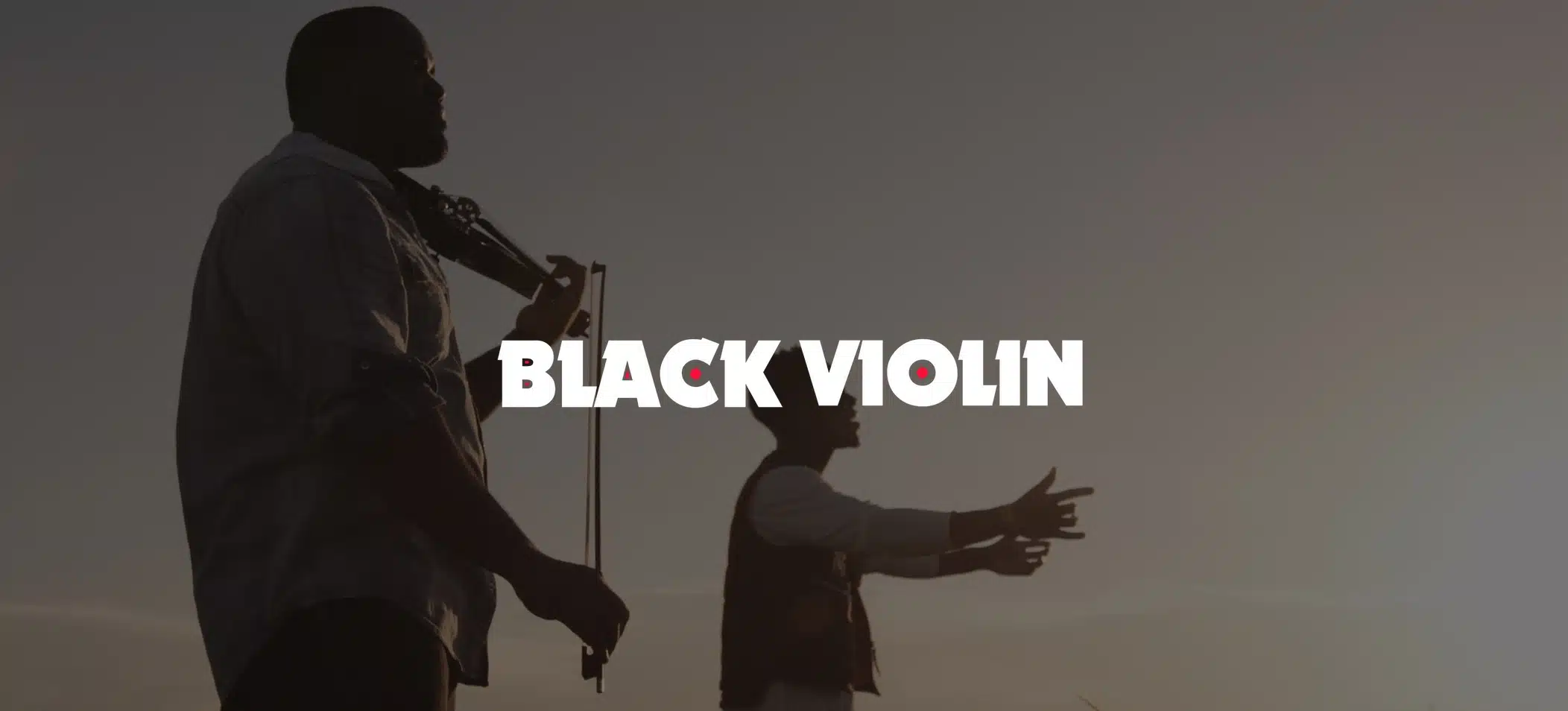 IU C&I Studios Portfolio and Page Red and white Black Violin logo on background closeup side profile of man playing violin with another man singing next to him