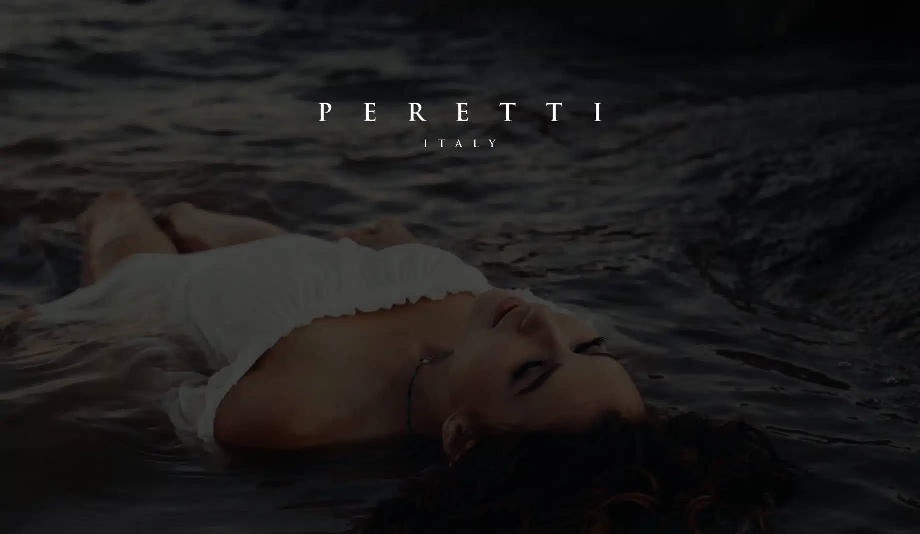 White Peretti Italy title on dimmed background of woman in a white dress laying in the water