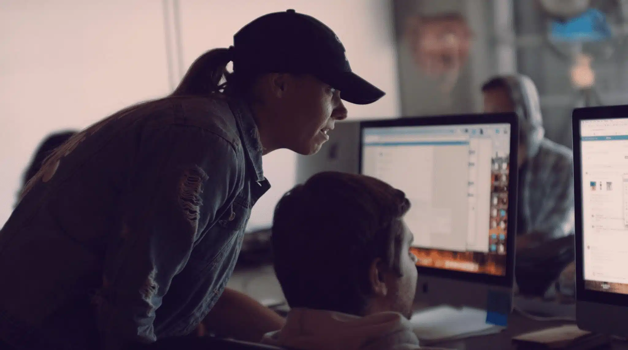 Amy Joy Miller Producer C&I Studios looking over shoulder at worker's computer display