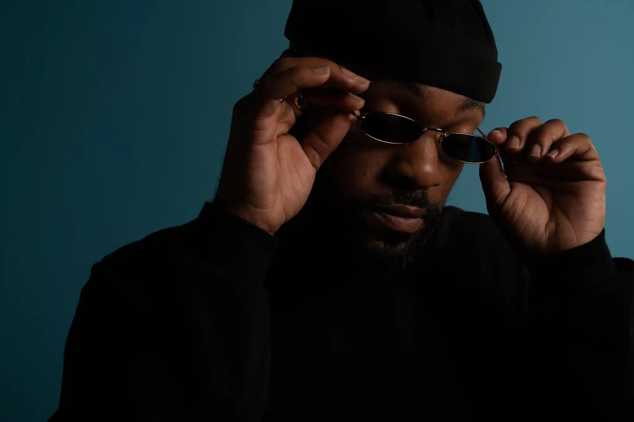 Christopher Brown Headshot with him wearing a black knit cap and black sweater adjusting his sunglasses