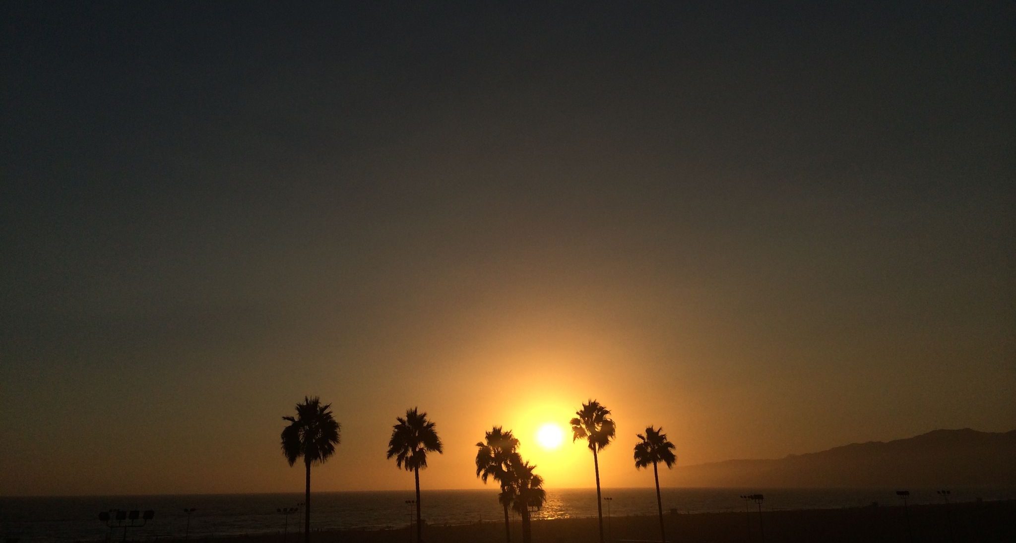 15 Recommended shooting locations for your next Los Angeles Video Marketing Campaign Silhouette of palms trees at sunset on a beach by water with mountain in the background