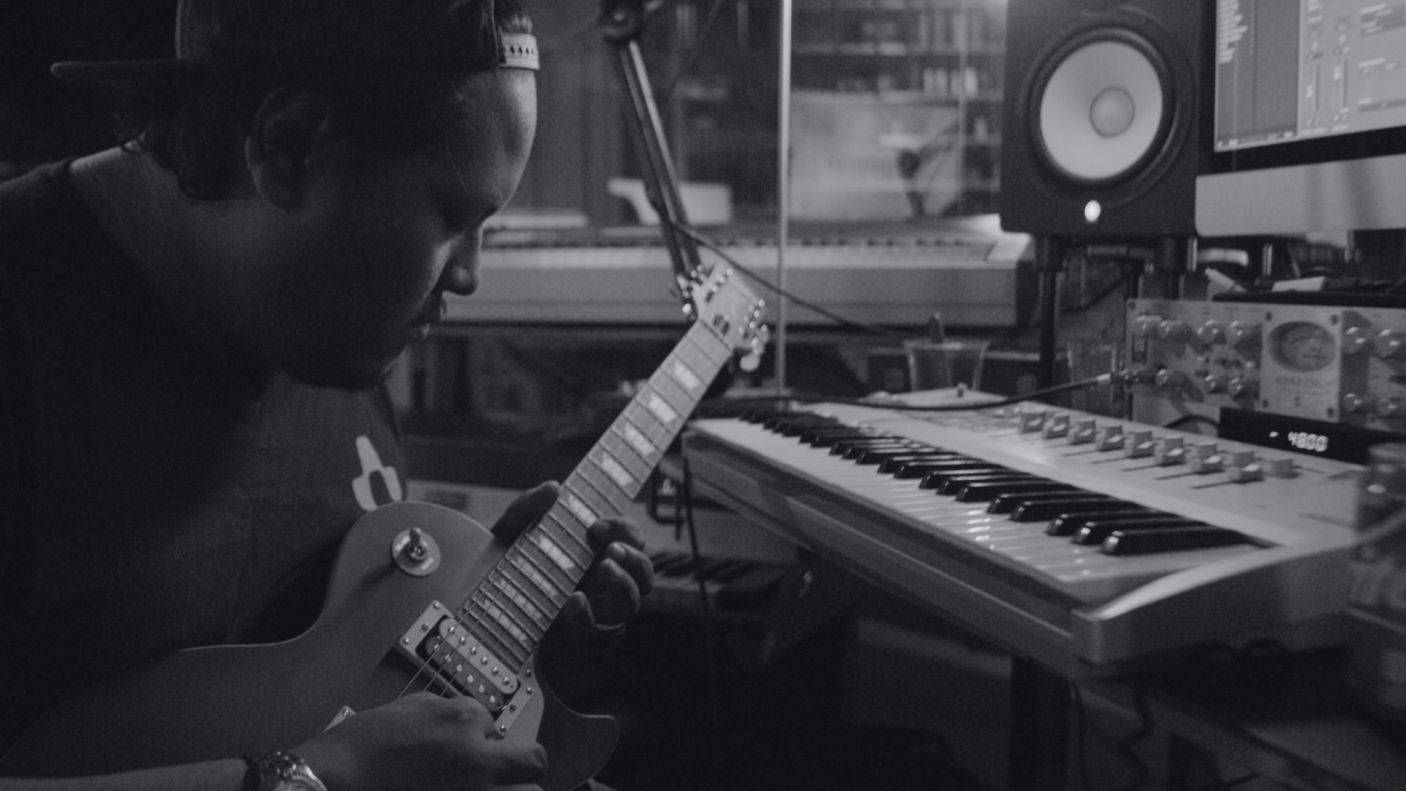 IU C&I Studios Page C&I Studios Blog Composer for Film Black and white side profile of man playing a guitar by a keyboard in a studio