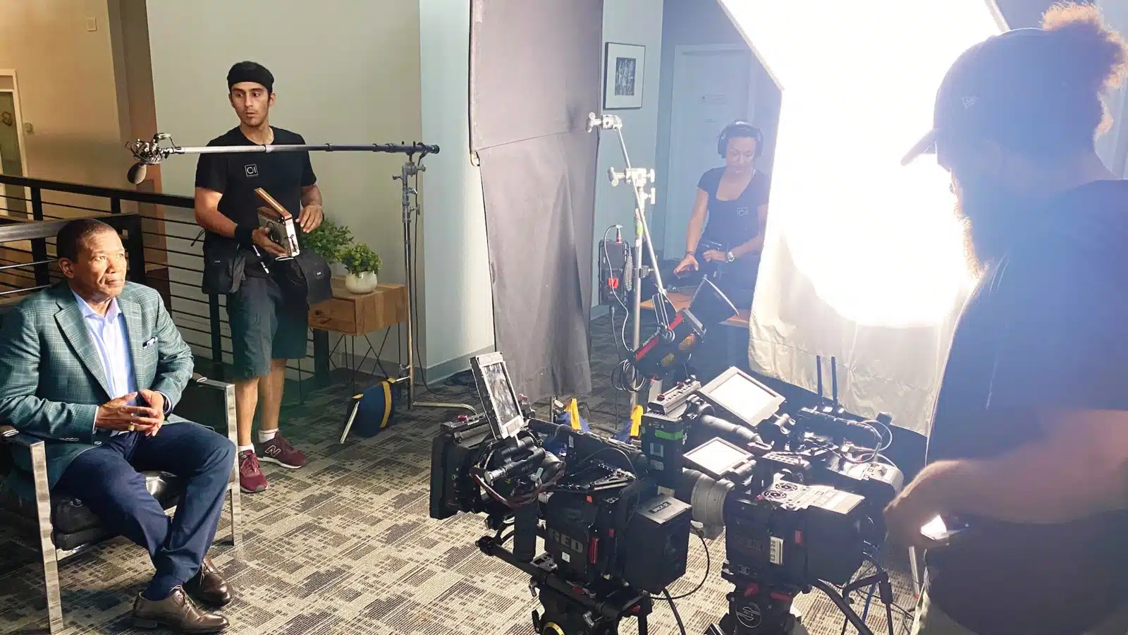 Grip essentials Group of two male and a female crew member getting ready to film a man sitting in a chair