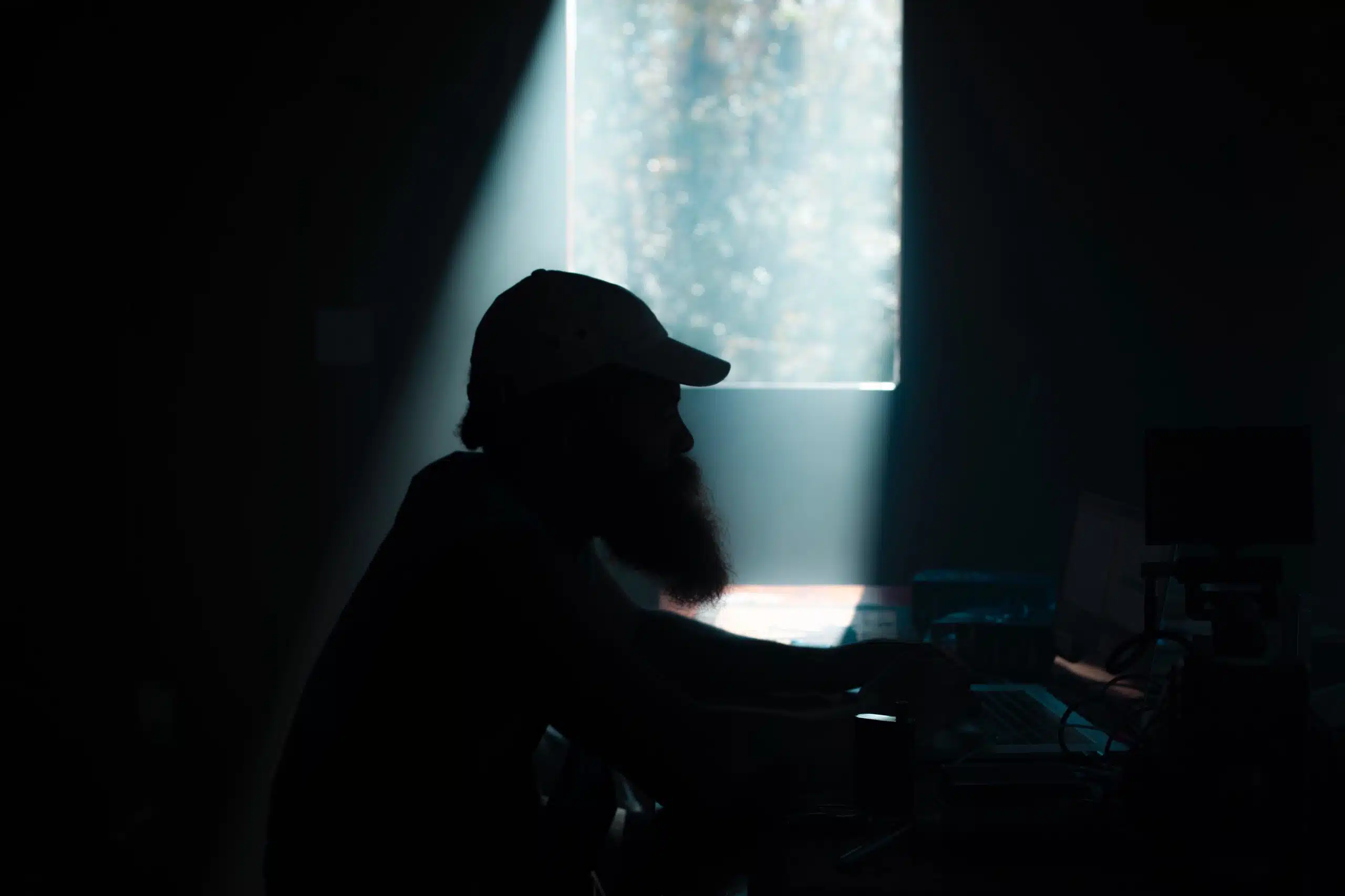 The Different Roles of DITs on a Film Set and How They Support the Camera Crew Side profile silhouette of male crew member working on a computer