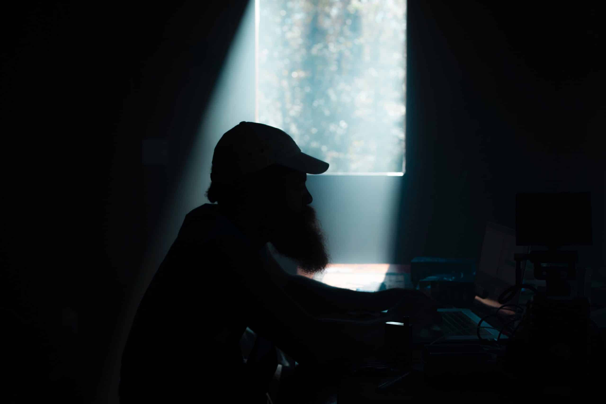 The Different Roles of DITs on a Film Set and How They Support the Camera Crew Side profile silhouette of male crew member working on a computer