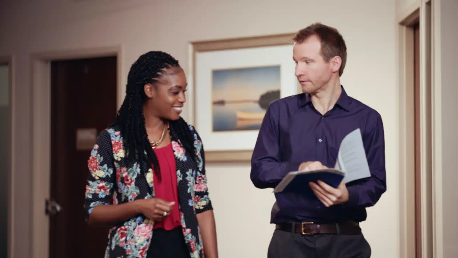 Man and woman looking at each other going over something in a notebook