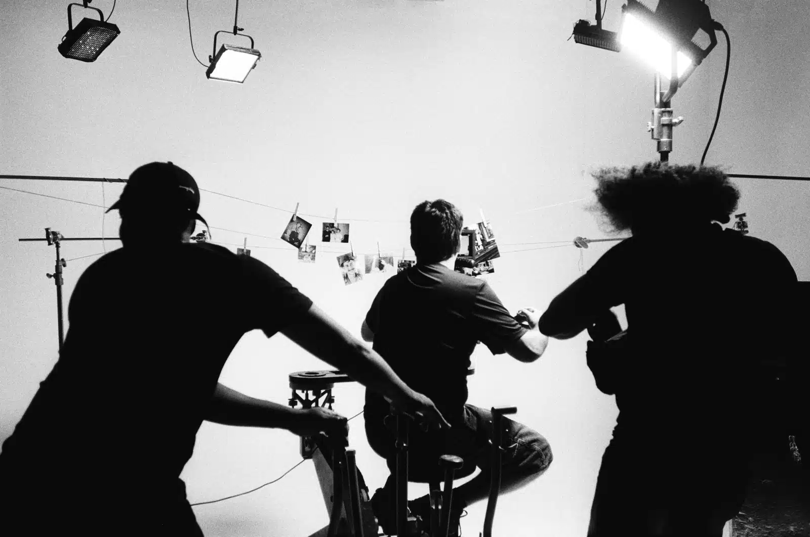 Repurpose Content Black and white view from behind of three male crew members filming pictures hanging on a clothesline with clothespins