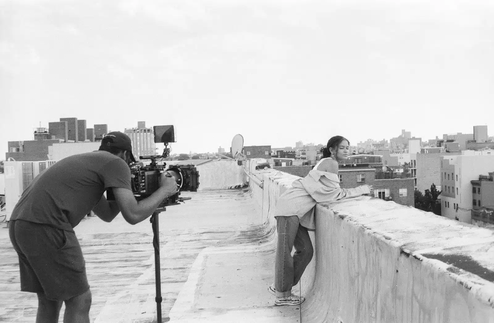 TikTok Creator Black and white side profile view of Joshua filming a woman leaning on a ledge on a rooftop of a building in a city