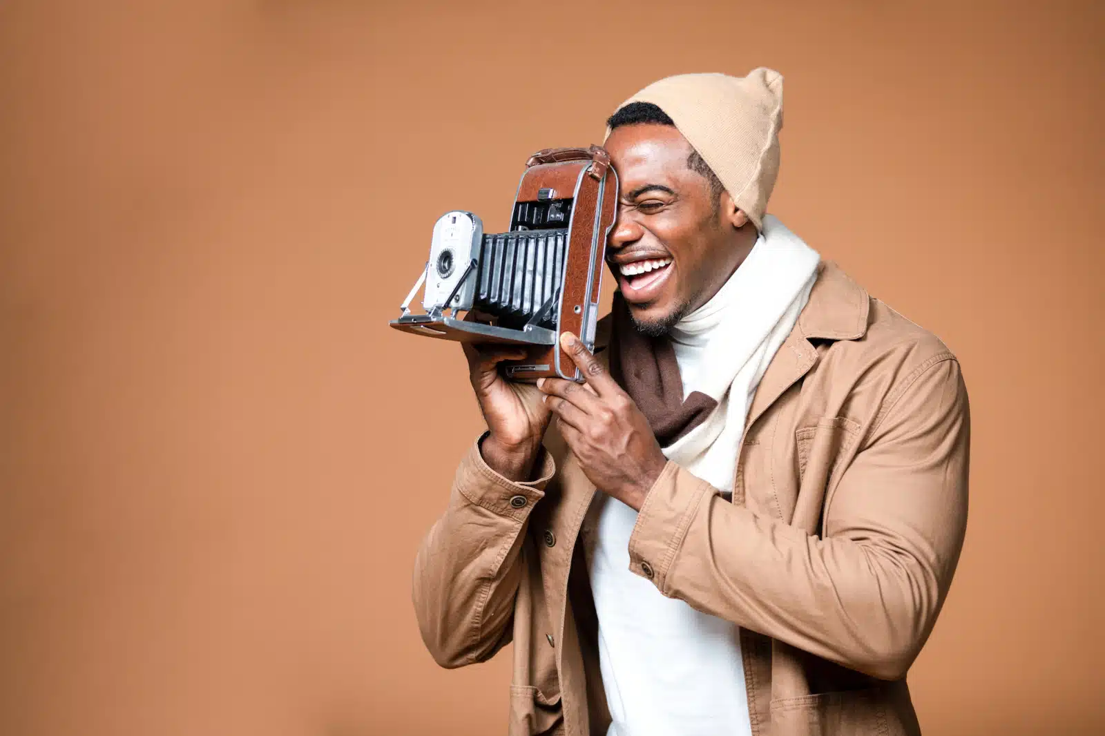 Amazon Product Video Side profile of man wearing a beige jacket and knit cap using a vintage camera smiling