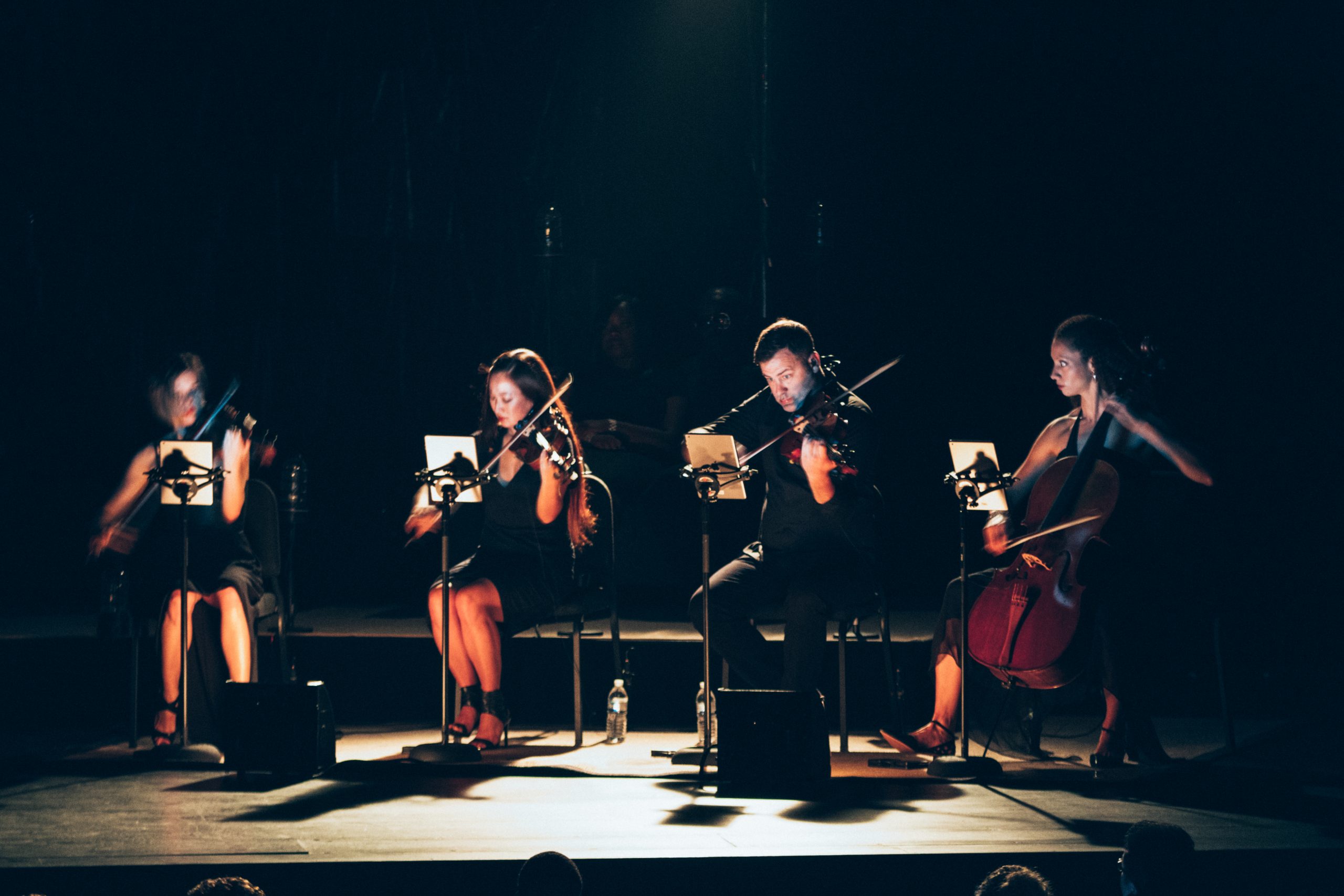 Closeup of three women and one man playing instruments at a John Legend concert