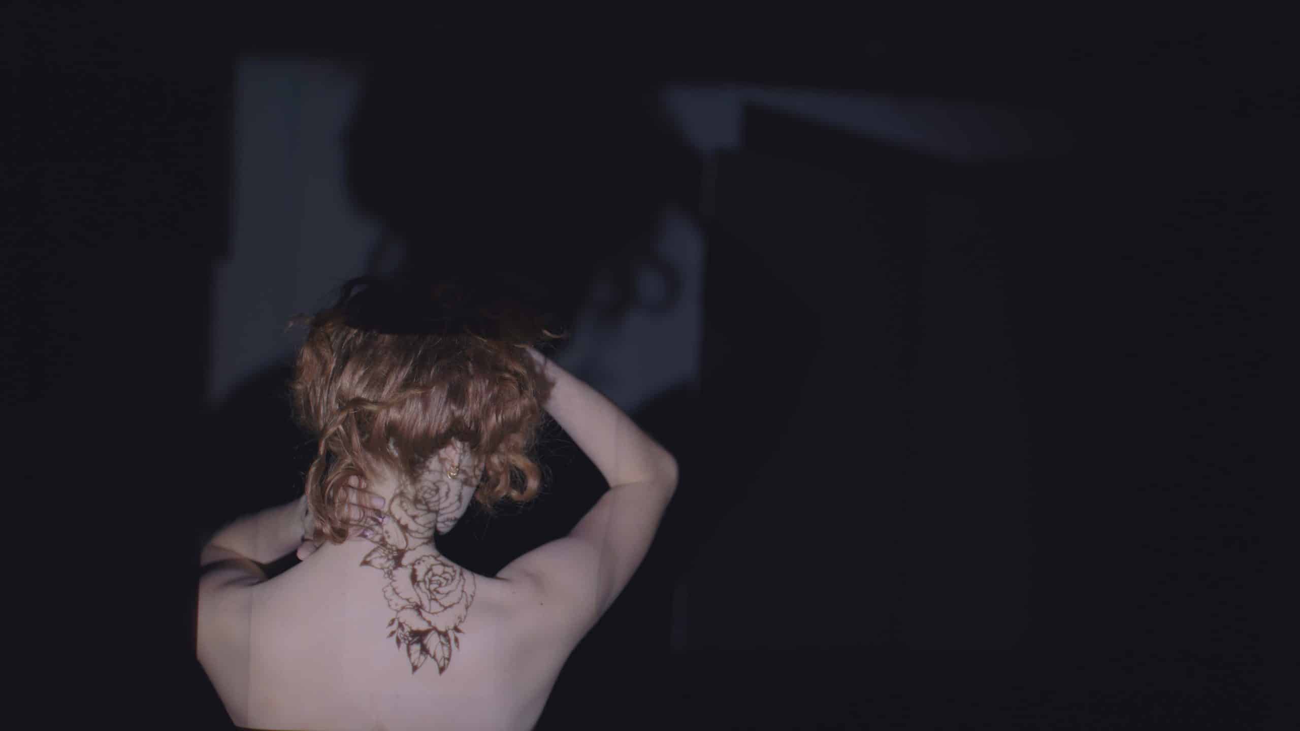 IU CI Studios Page Artwalk projection tattoo shoot with view of tattoo on back of woman holding her blond hair up