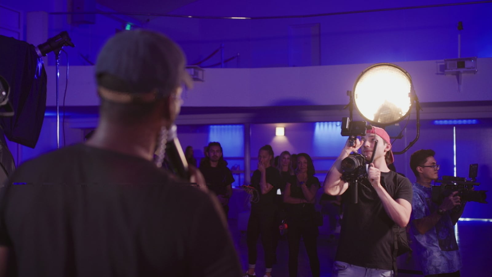 Male crew member filming a person in a studio